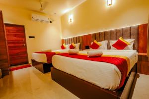 ゴカルナにあるCozy Gokarna Beach Stayの赤と黄色の枕が付くベッド2台が備わるホテルルームです。 +7枚の写真