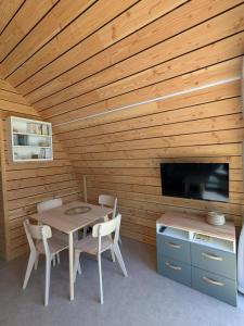 a dining room with a table and a tv at La cabane de romane in Le Bleymard