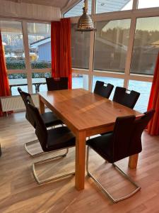 Una mesa de comedor de madera con sillas negras y ventanas. en Ferienhaus Möwenstübchen Grömitz, en Grömitz