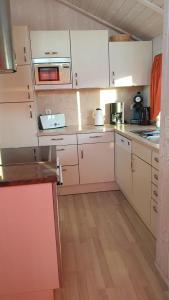 cocina con armarios blancos y suelo de madera en Ferienhaus Möwenstübchen Grömitz, en Grömitz