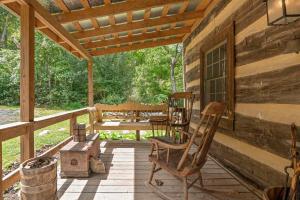a porch of a wooden cabin with a table and chairs at Historic 1802 Forge Home by North River & Trails in Capon Bridge