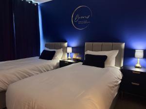 two beds in a hotel room with blue lights at Chelsea Thames View Suite in London