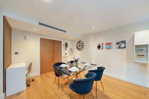 a dining room with a glass table and blue chairs at Chelsea Thames View Suite in London