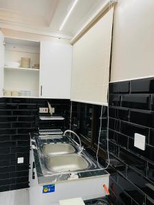 a kitchen with a sink and black tiled walls at Swara Apartment, Block 1, Apartment A1 in Nanyuki