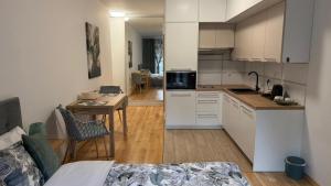 eine Küche mit weißen Schränken und einem Tisch in einem Zimmer in der Unterkunft Green Leaf Studio in Breslau