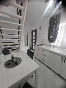 a large white kitchen with a table and stairs at Casuța Râului in Zărneşti
