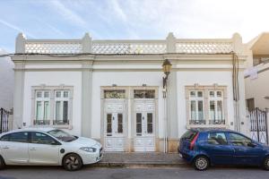 two cars parked in front of a white building at Blife Galiya private house in Faro