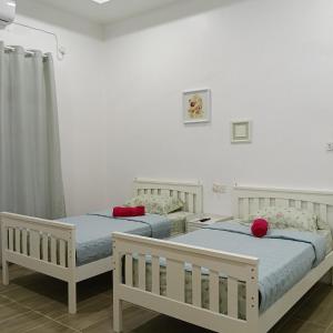 two beds in a room with white walls at Lu&Lu Rooms & Homestay in Dungun