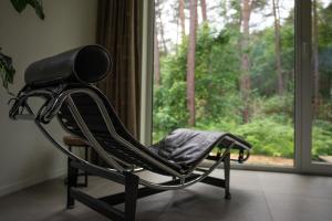uma cadeira de balanço preta em frente a uma janela em White Box em Gierle