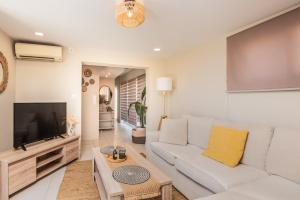 a living room with a white couch and a tv at Filoxenia City Apartment in Zakynthos Town