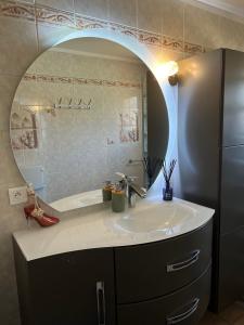 a bathroom with a sink and a large mirror at La maison de Claude avec terrasse et piscine in Crest