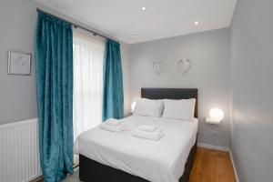 a bedroom with a large white bed with blue curtains at Rose Street flat in Edinburgh