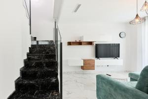 a living room with a staircase and a tv at Rojales Golf House - by Welcomely in Rojales +16 photos