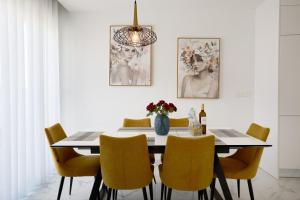a dining room with a table and yellow chairs at Rojales Golf House - by Welcomely in Rojales