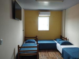 deux lits dans une chambre avec une télévision au mur dans l'établissement Pousada São Benedito, à Cachoeira Paulista 28 autres photos