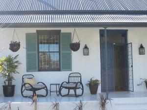 a porch with two chairs and a window at B's Cottage Swellendam in Swellendam