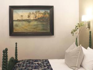 a painting hanging on a wall above a bed at B's Cottage Swellendam in Swellendam