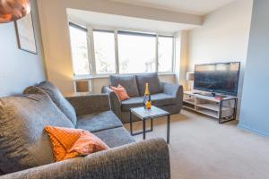 a living room with two couches and a flat screen tv at Spacious 2 Bedroom Apartment in Oxford, Near Hospitals & University Parks in Oxford