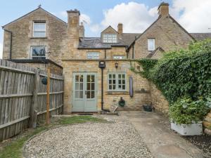 ein altes Backsteinhaus mit einem Holzzaun in der Unterkunft The Cottage in Cheltenham