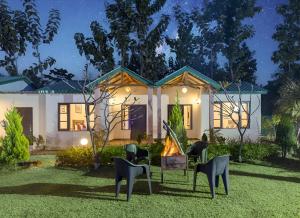 ein Haus mit Stühlen und einem Feuer im Hof in der Unterkunft Corbett Mid Forest House - 1Min Walk to River & Jungle Safari in Rāmnagar