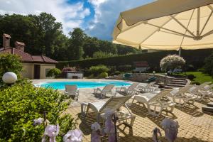 a group of chairs and an umbrella next to a swimming pool at Fazenda na Goncharakh in Ganʼchary