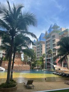パタヤ・サウスにあるgrande caribbean condo by stays innのヤシの木と建物のあるスイミングプール