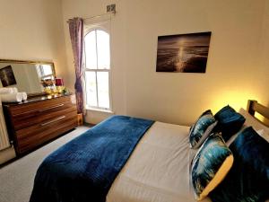a bedroom with a bed with blue sheets and a window at A modern hideaway in the heart of Whitstable in Whitstable