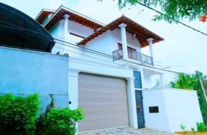 a white house with a garage at Heaven Hill Guesthouse in Weligama