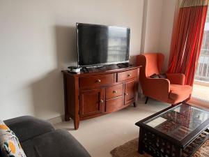 a living room with a flat screen tv on a wooden dresser at MountainNest Wrapped in Clouds in Dehradun