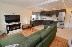 a living room with a green couch and a kitchen at Lodge at The Old Barracks in Athenry