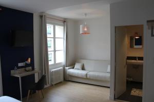 a living room with a white couch and a window at Hôtel La Fontaine Caen Centre in Caen