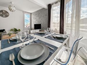 a dining room with a table with plates and wine glasses at Proche Paris et Disneyland T2 calme avec Terrasse in Noisiel