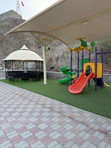 a play area with a playground with a slide at Alhara Lodge استراحة الحارة in Hatta