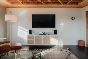 a living room with a flat screen tv on a white wall at Luxe Gabel Farmhouse Fire Pit & Country Views in Callicoon