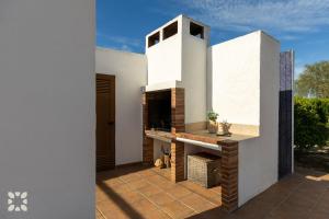 テウラーダにあるVilla Canela by Abahana Villasの白い家の中のパティオ(暖炉付)