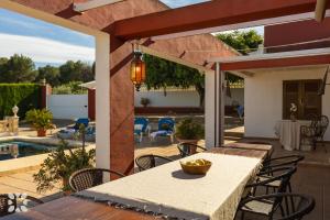 テウラーダにあるVilla Canela by Abahana Villasのテーブルと椅子とプールのあるパティオ