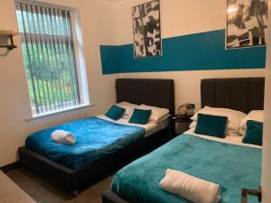 deux lits dans une chambre avec du bleu et du blanc dans l'établissement Tudors eSuites - Three Bedroom House - #16B, à Sedgley