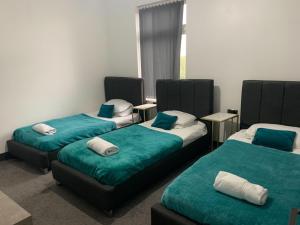 Cette chambre comprend 3 lits avec des draps bleus et blancs. dans l'établissement Tudors eSuites - Three Bedroom House - #16B, à Sedgley