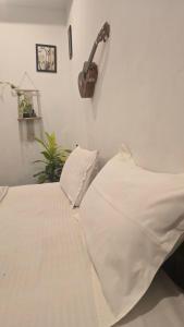 a bedroom with a white bed with a guitar on the wall at Cascara Beach Resort in Varkala +8 photos