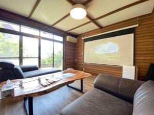 a living room with a table and a large screen at Boogie Garden in Yugawara