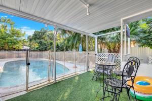 Un patio con mesa y sillas y una piscina. en Tranquil Pool Home in Hollywood Close to Beach Airport, en Hollywood