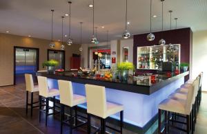 un bar en un restaurante con sillas blancas en Leonardo Hotel Völklingen-Saarbrücken, en Völklingen