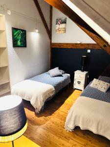 a room with two beds and a table in it at La Maison Rouge Au coeur de la ville. in Riquewihr