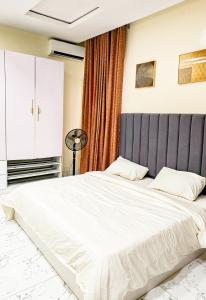 - une chambre avec un grand lit blanc et une tête de lit gris dans l'établissement 4 bed duplex in prime location, à Ibadan 24 autres photos