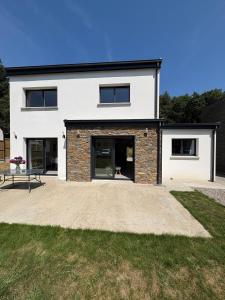 a white house with black windows and a patio at Maison neuve cosy à 20 min des plages #lorient #cosy in Pont-Scorff