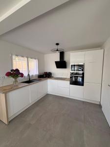 a white kitchen with white cabinets and a sink at Maison neuve cosy à 20 min des plages #lorient #cosy in Pont-Scorff