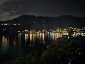 a view of the water at night with a city at Botanic Garden Lake Como in Blevio