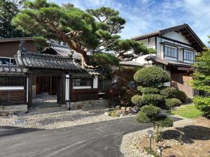 a house with a pine tree in front of it at 離れの宿 かぶろの庭 in Matsukawa
