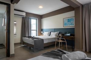 a bedroom with a bed and a desk with a chair at Lym Flat Hotel in Uberlândia +28 photos