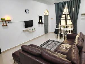 a living room with a leather couch and a tv at Roomstay Kak Ton DELUXE ROOM in Kuala Terengganu